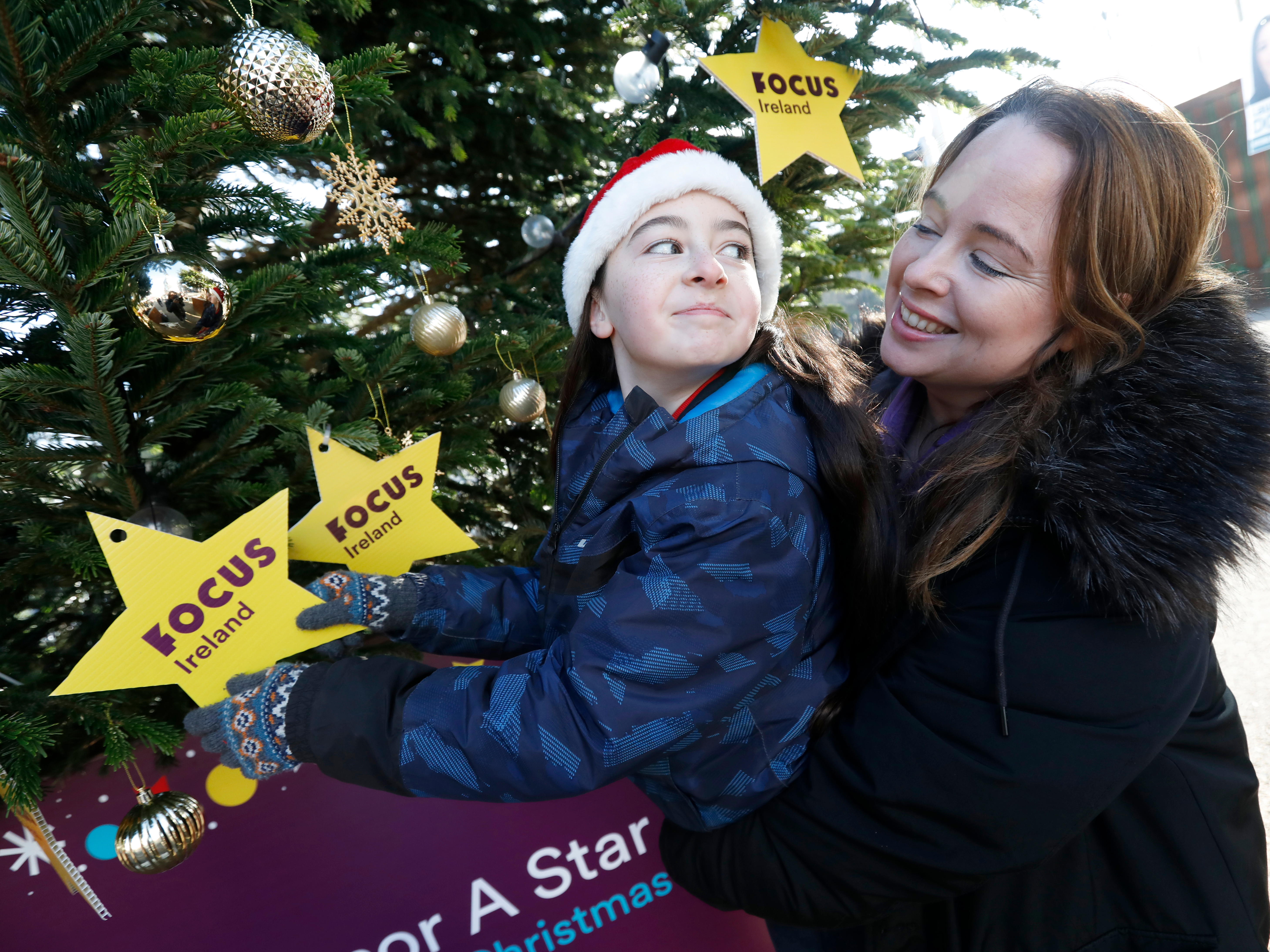 Mother lifting her child up to reach a star on the focus ireland tree Mother lifting her child up to reach a star on the focus ireland tree