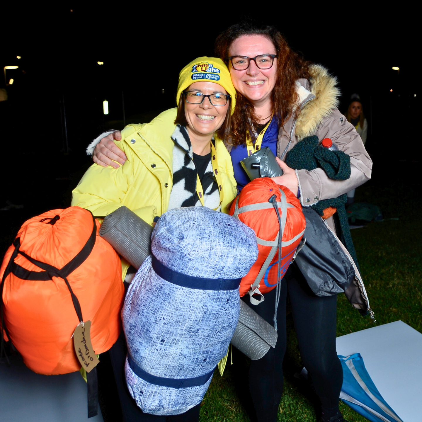 Two Community Sleep out members holding sleeping bags and